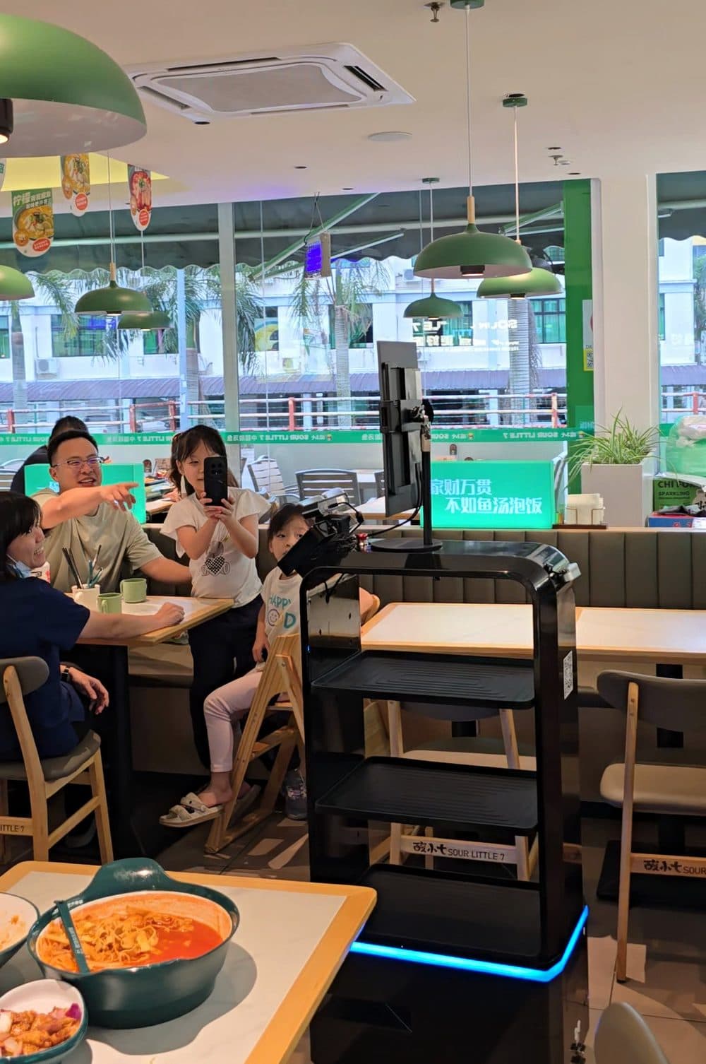 A girl records FL1 on her phone at a table in Sour Little 7